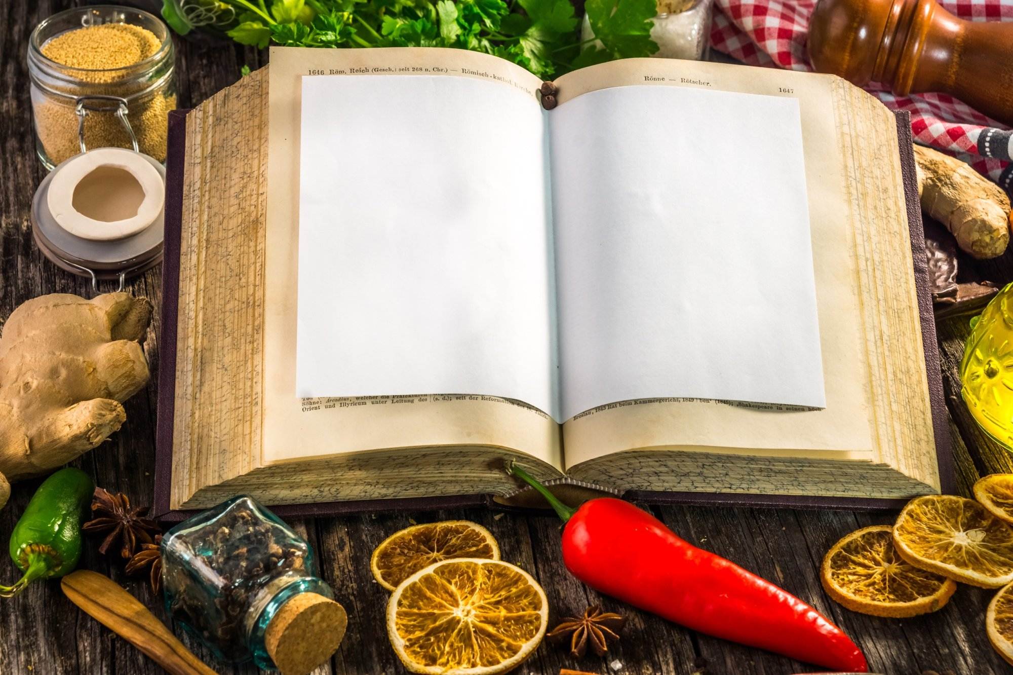 Open cookbook with spices on wooden table.